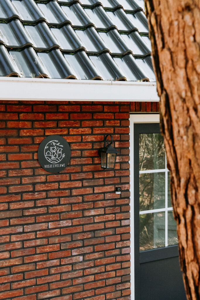 Doorkijkje naar de voordeur, buitenlamp en naambordje